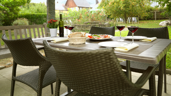 Tisch unter der Pergola im Garten des Hotels mit regionalem Weisswein und leichten Speisen.